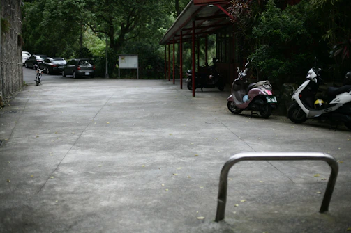 Parking area outside the kost under a clear blue sky with bicycles and motorbikes.