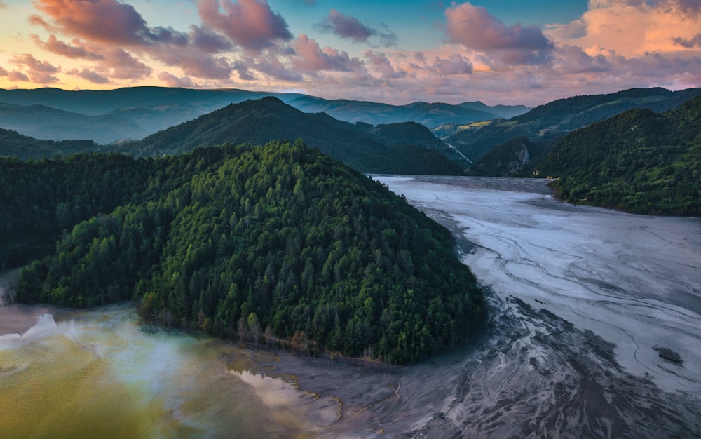 green mountain beside body of water under cloudy sky during daytime