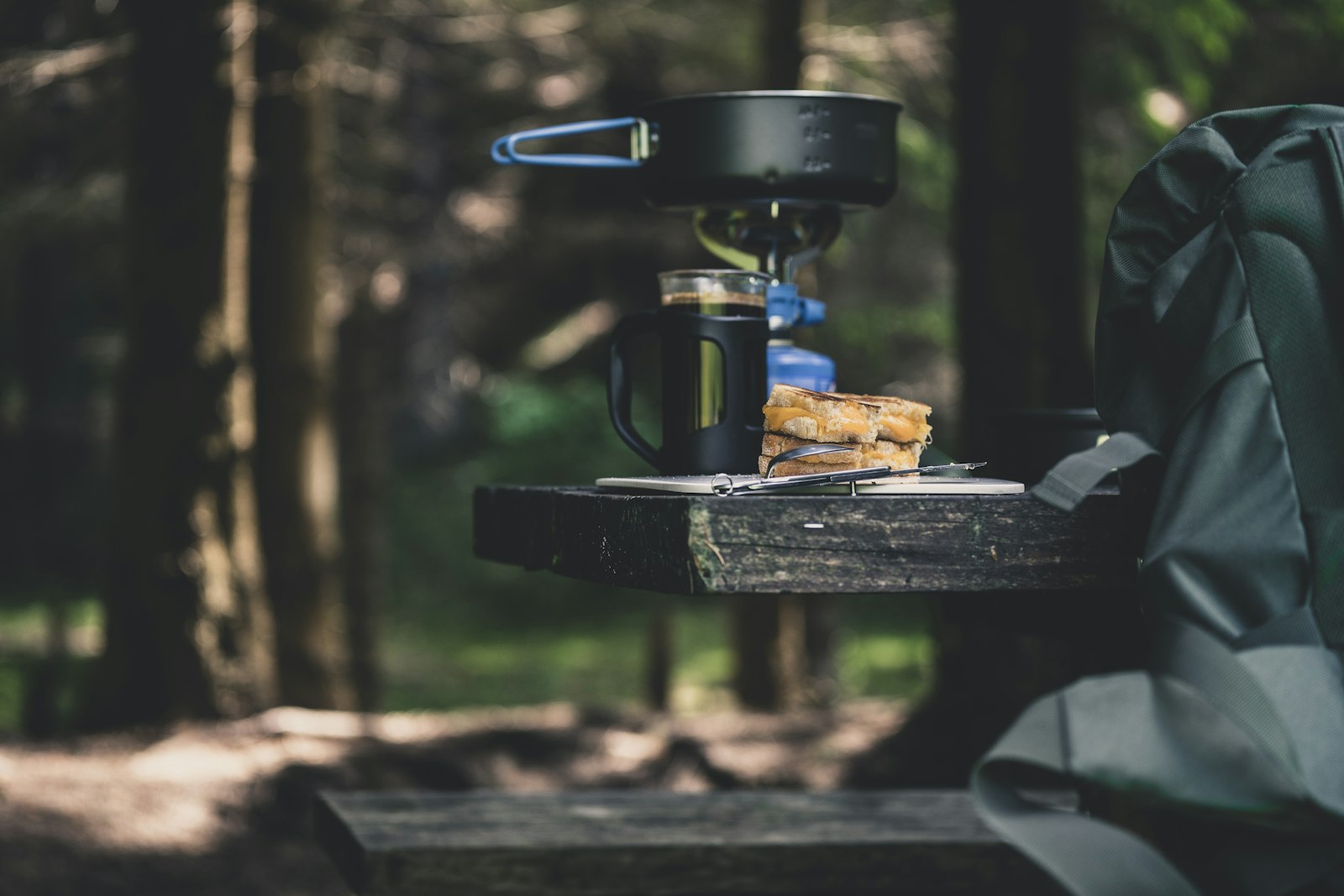 Une popote sur un petit réchaud, près d’une cafetière, en forêt