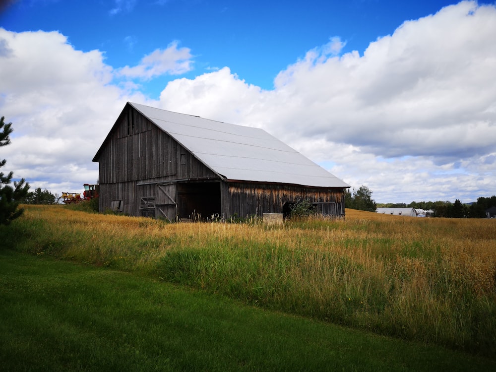 brown wooden barn on green grass field under blue sky during daytime