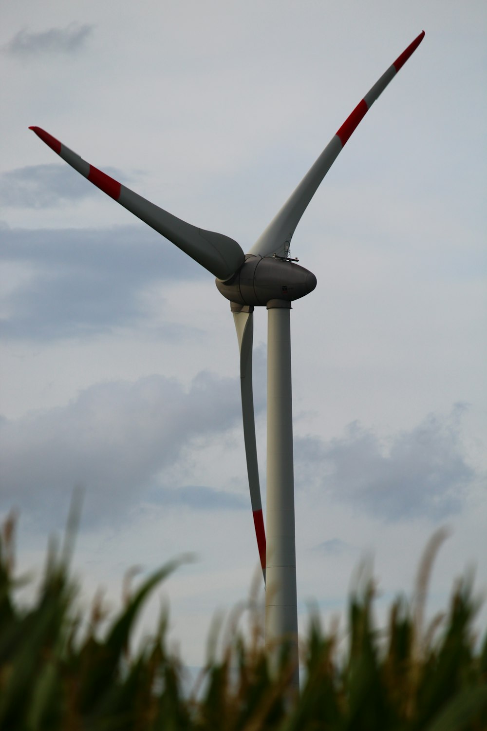 white wind turbine under white clouds during daytime