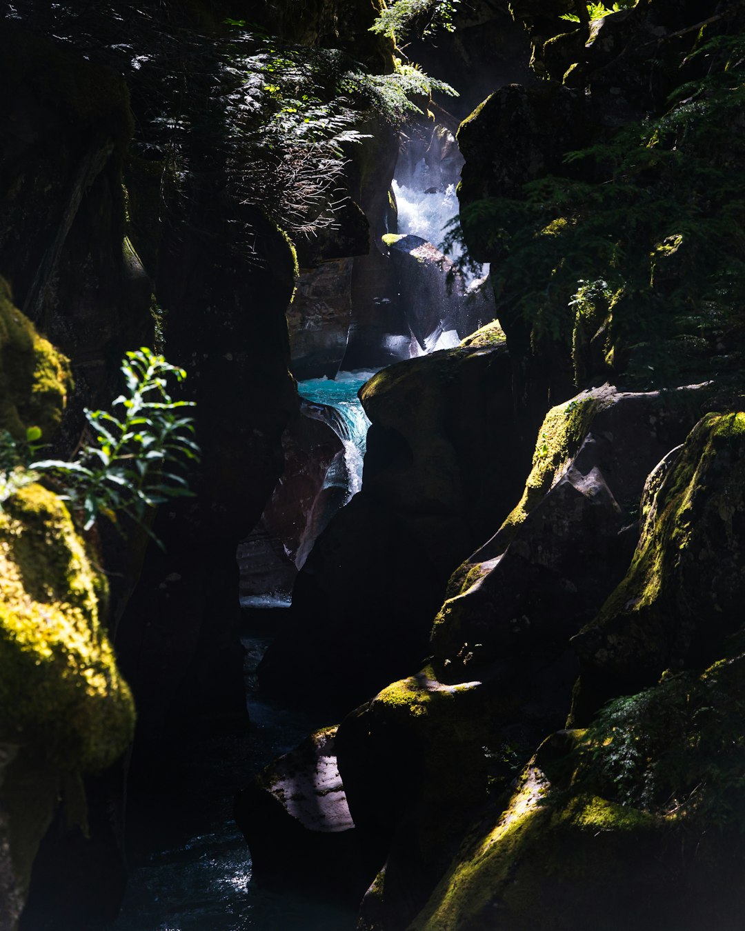 person in white shirt and blue denim jeans standing on rock near waterfalls during daytime