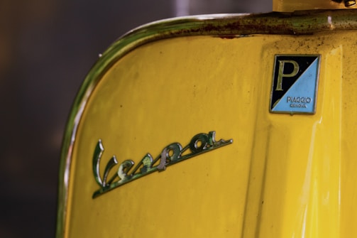 The golden Medusa logo shining subtly on the side of the vintage Piaggio Ape.