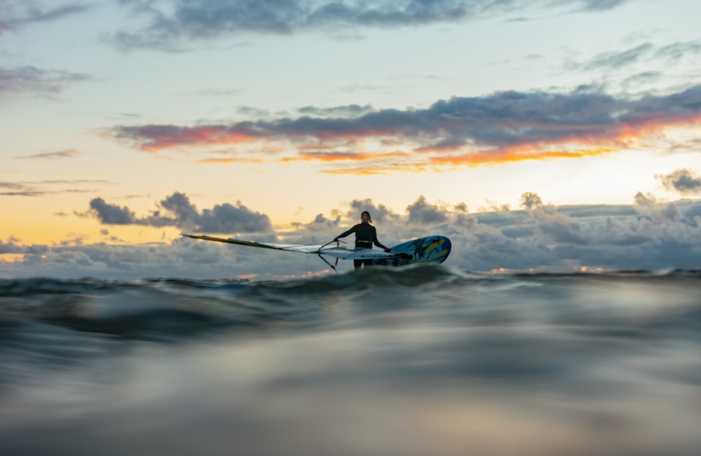 silhouette dell'uomo che cavalca sul kayak blu sul mare durante il tramonto