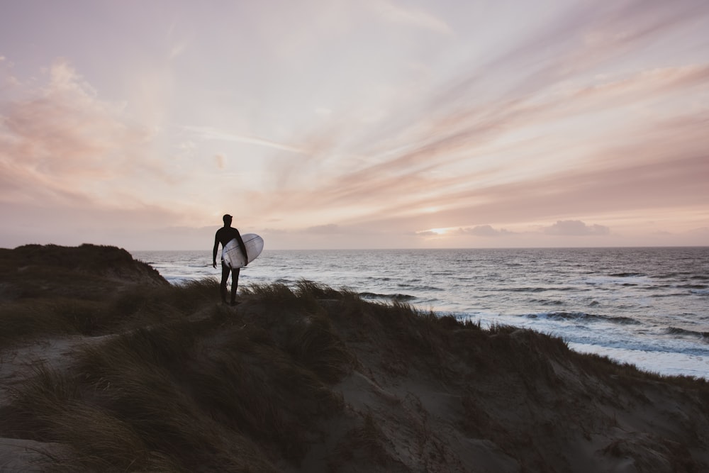 man in black shirt and pants walking on seashore during daytime