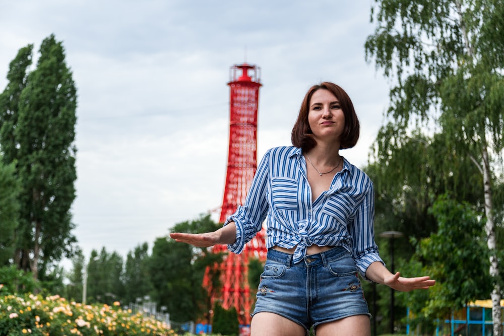 woman in blue and white striped button up shirt and blue denim shorts standing on yellow