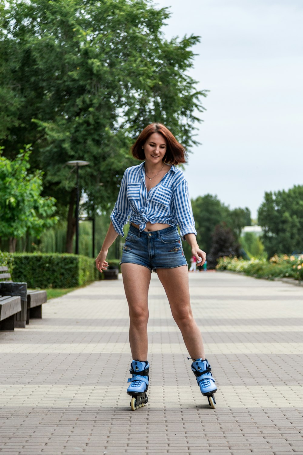 woman in blue denim shorts and white and black striped long sleeve shirt standing on gray