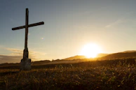 brown cross on green grass field during sunset