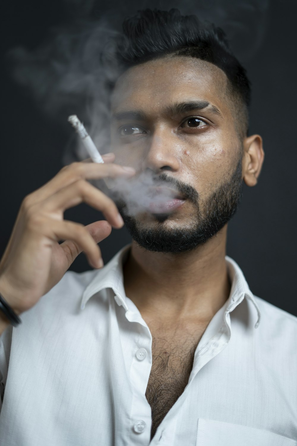 homem na camisa social branca que fuma o cigarro