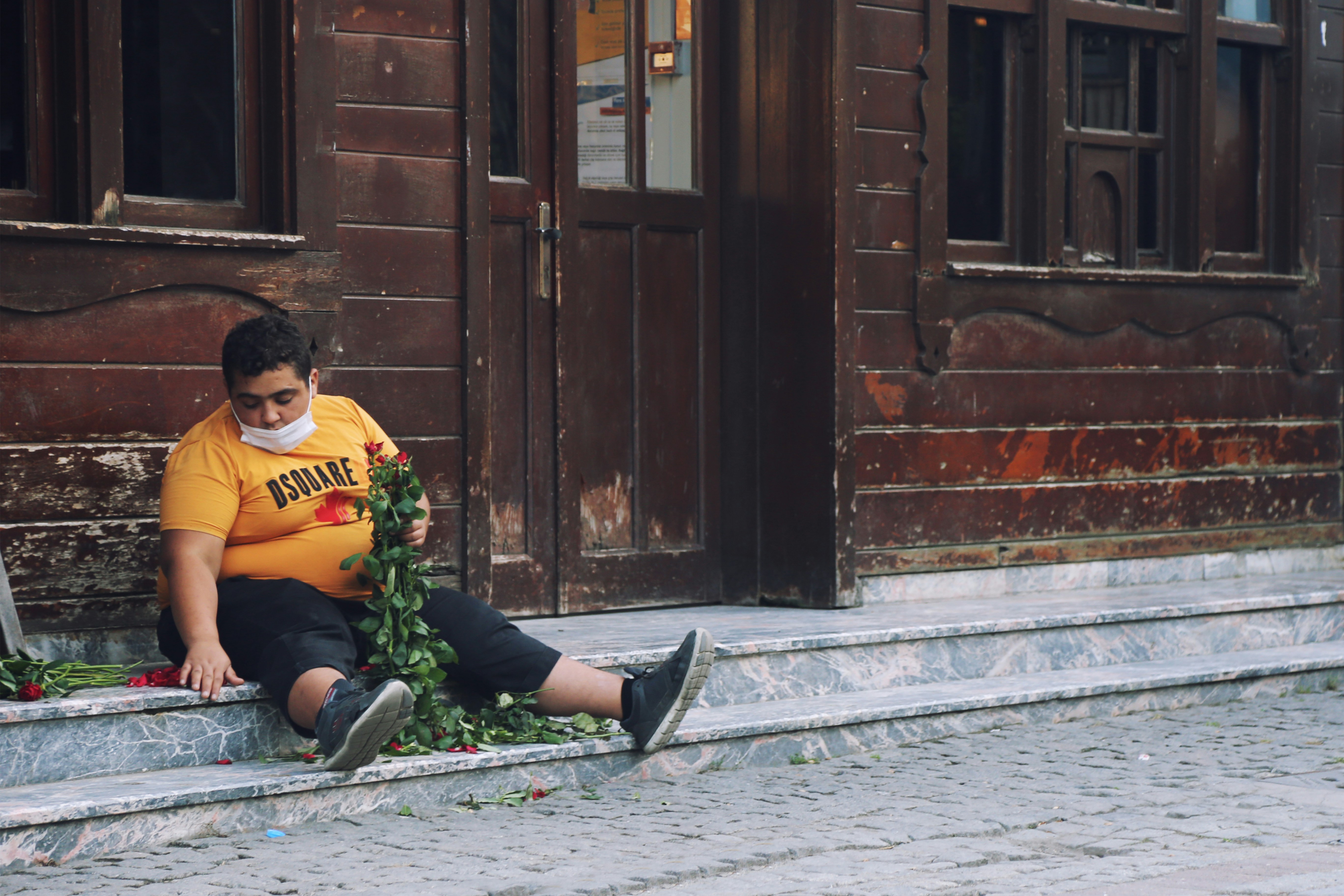 woman in yellow and black long sleeve shirt sitting on gray concrete floor