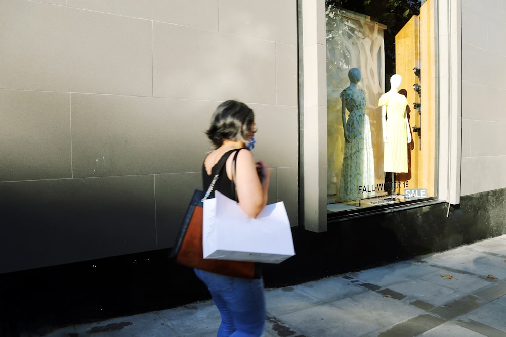 Mujer con camisa blanca y jeans de mezclilla azul de pie frente al espejo