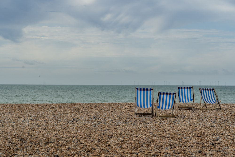 낮 동안 해변에 파란색과 흰색 해변 의자
