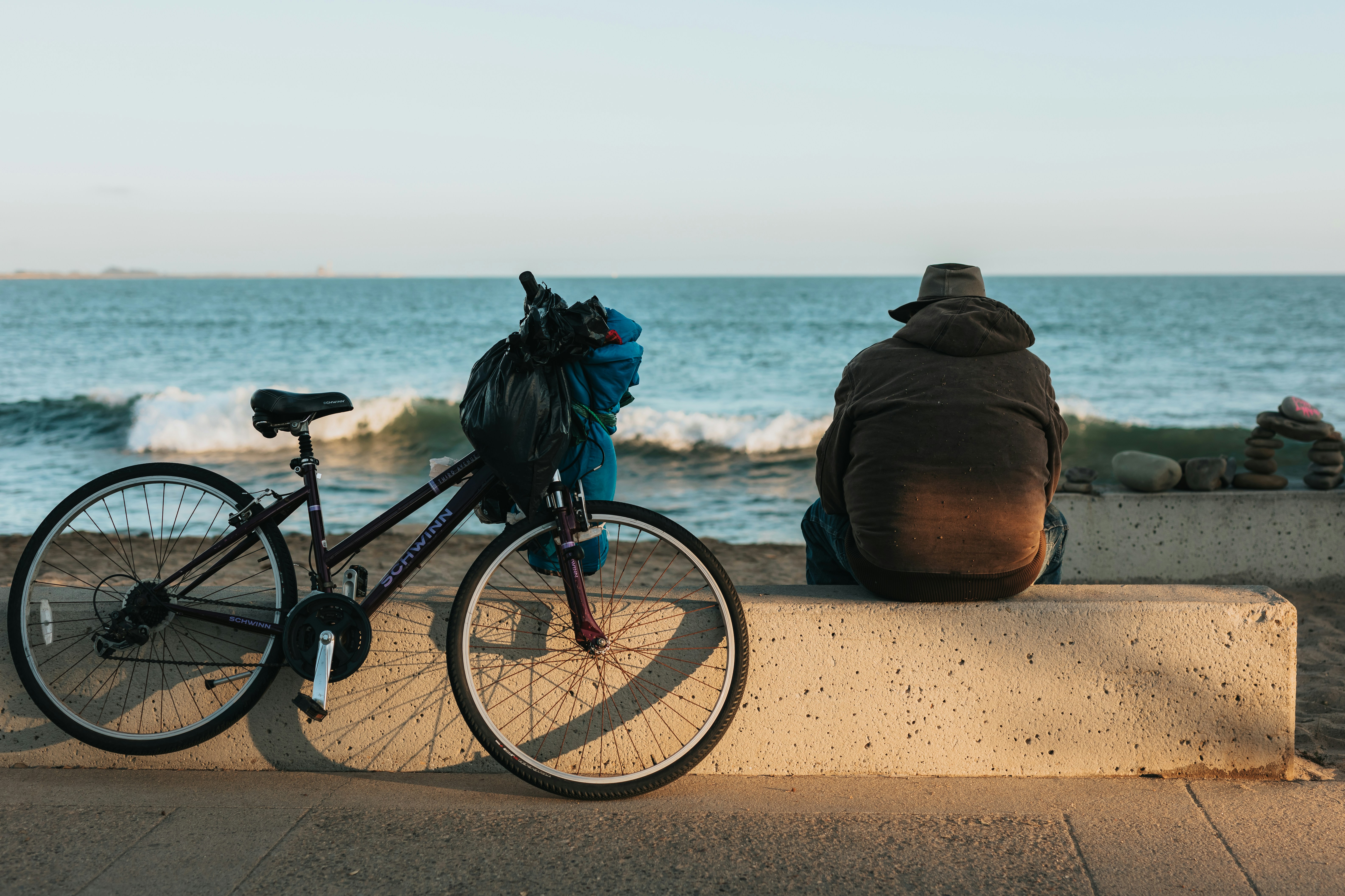 black bicycle with black backpack on brown sand near body of water during daytime
