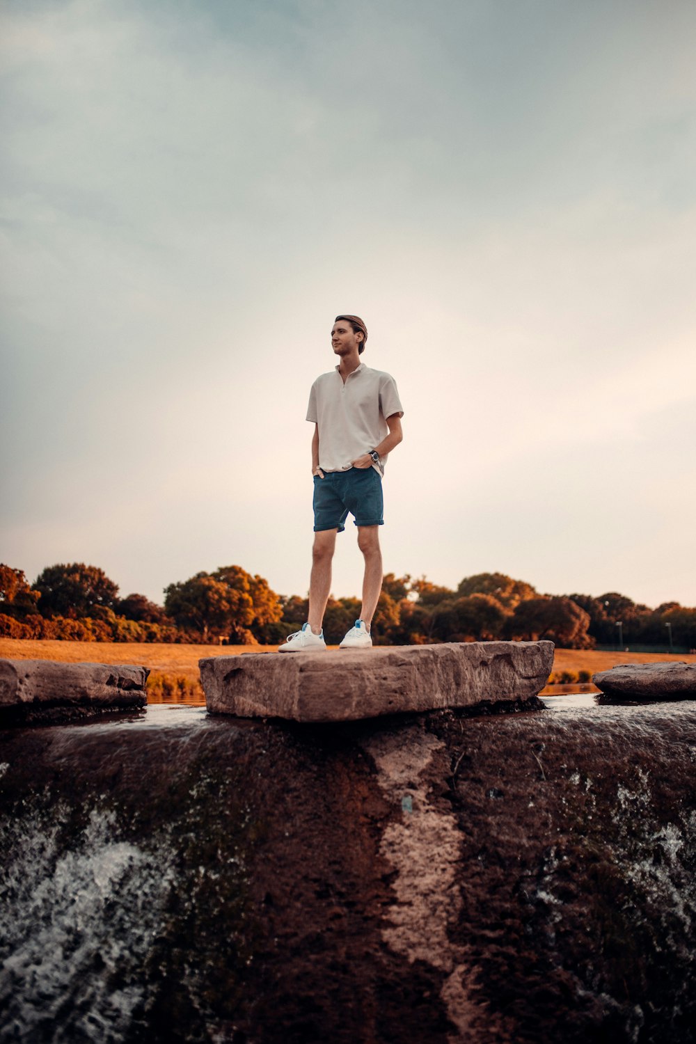 man in white t-shirt standing on brown rock during daytime