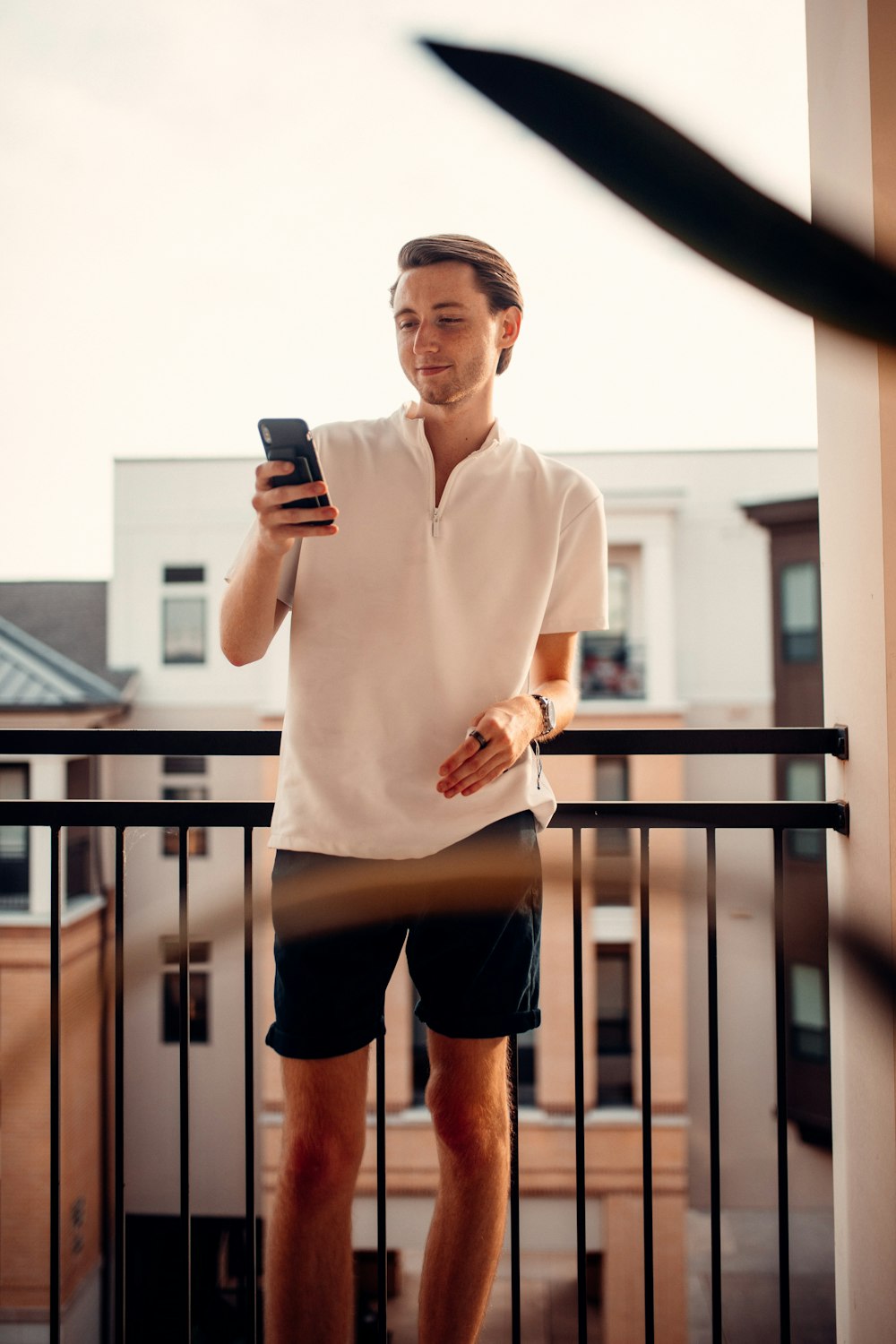 woman in white long sleeve shirt and black shorts holding black smartphone