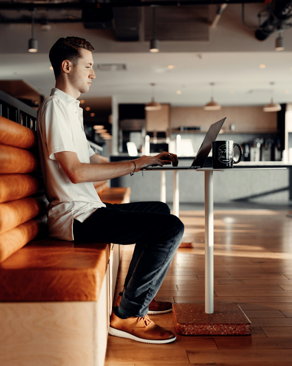 man in white t-shirt and blue denim jeans sitting on brown leather couch