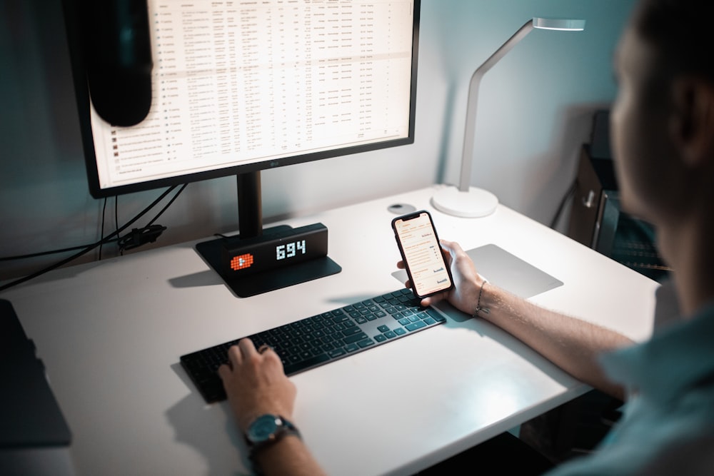 person holding white smartphone on white table