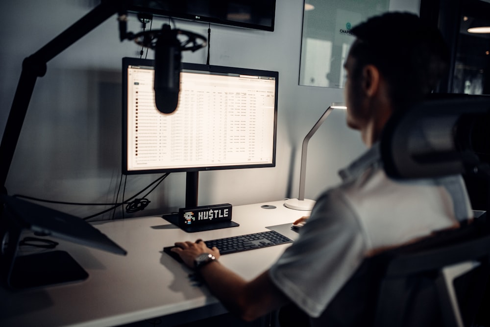 Mann im weißen Poloshirt sitzt vor dem Computer