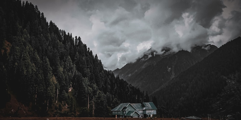 green house surrounded by trees near mountain under cloudy sky during daytime