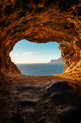 brown cave near body of water during daytime