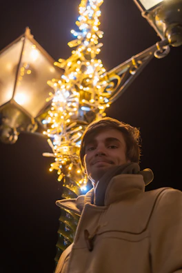 Evening shot of a Lumina Apparel coat hanging on a vintage lamp post with city lights glowing behind.