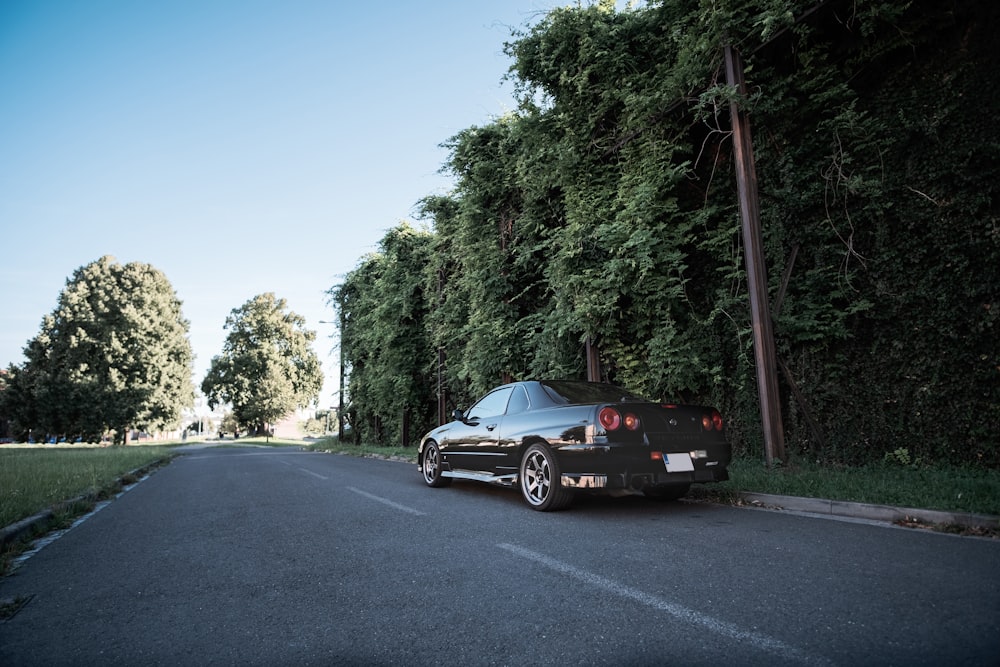 black coupe on road near green trees during daytime