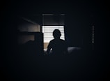 A suggestive silhouette of a person reclining on a bed with soft shadows.