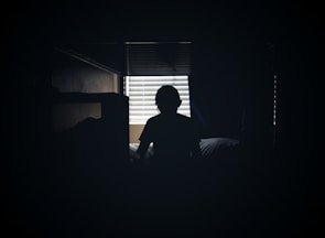 A suggestive silhouette of a person reclining on a bed with soft shadows.