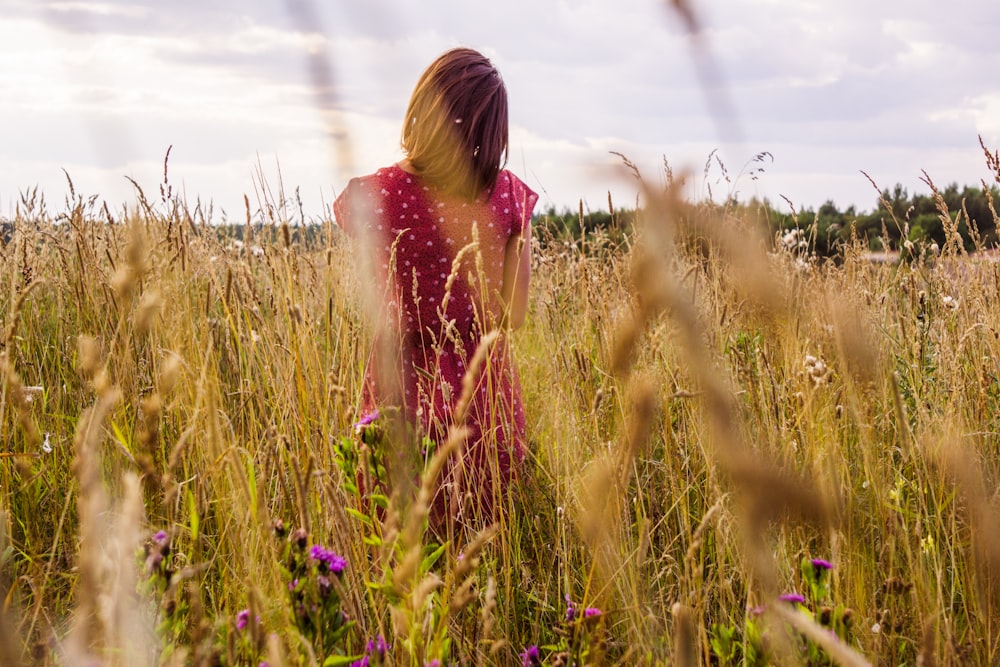 woman in pink dress standing on green grass field during daytime