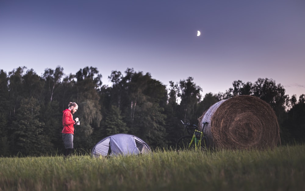 woman in red jacket standing beside white dome tent during night time