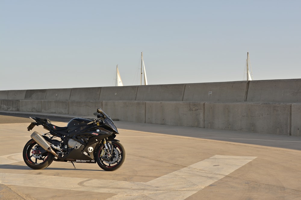 motocicleta preta estacionada no chão de concreto marrom