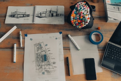 An assortment of high-quality architectural drafting tools and blueprints spread out on a desk.