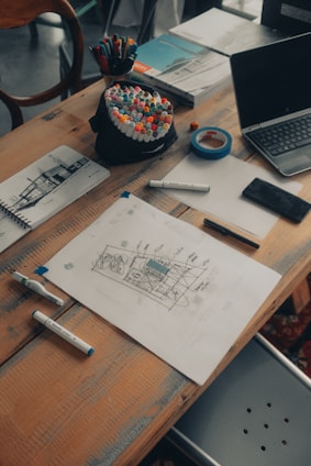 A creative workspace with storyboards, scripts, and digital art tools spread across a wooden table.