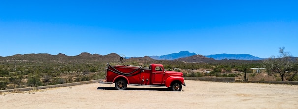 A cherry red and white truck parked at a scenic location.