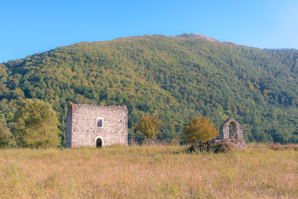 Maison en brique brune sur un champ d’herbe verte près de la montagne pendant la journée