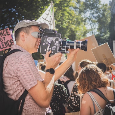 man in brown and white checked button up shirt taking photo of people during daytime