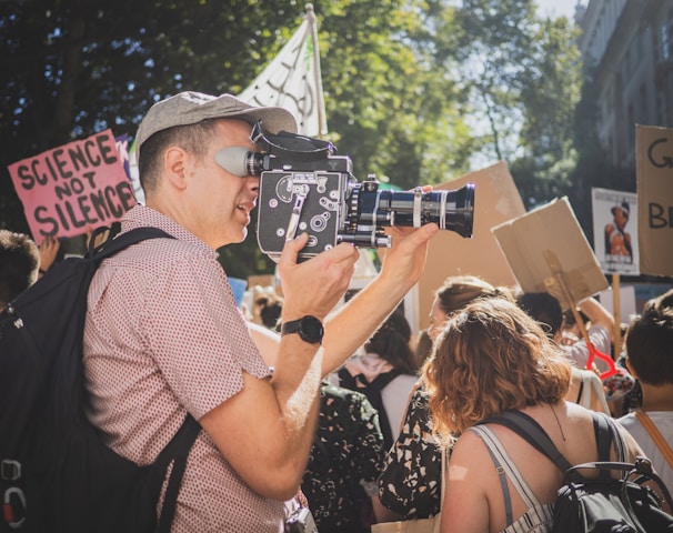 man in brown and white checked button up shirt taking photo of people during daytime