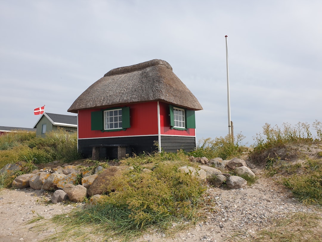green and brown house near brown rock formation under white clouds during daytime, Beautiful little beach house