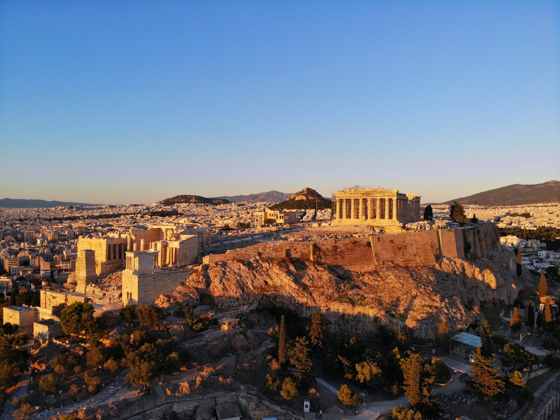 The Acropolis at golden hour, the city running out to the hills behind it.