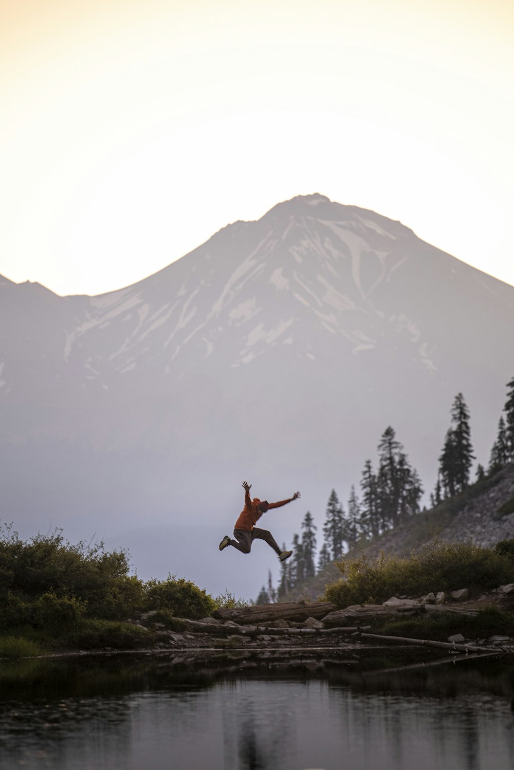 man jumping on rocky mountain during daytime