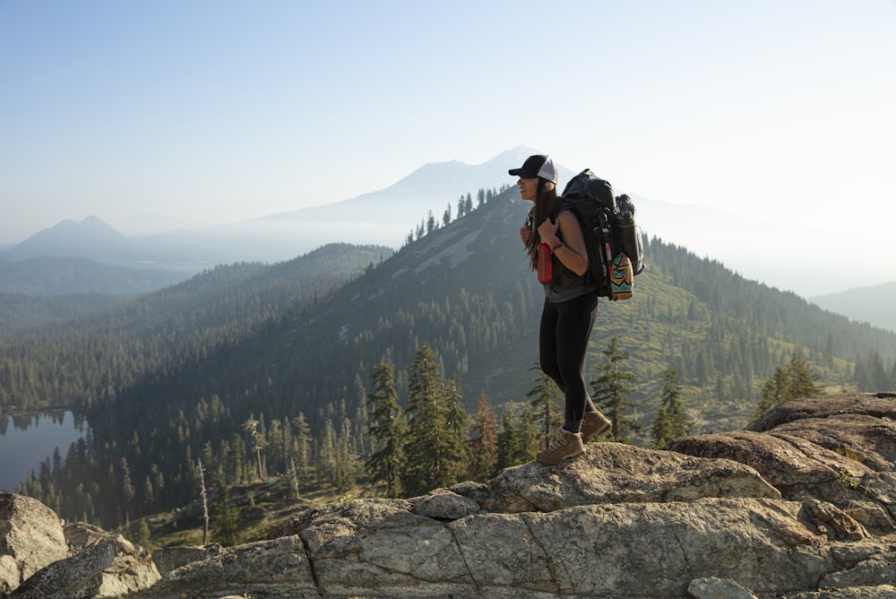 man in black jacket and black pants standing on rock formation during daytime