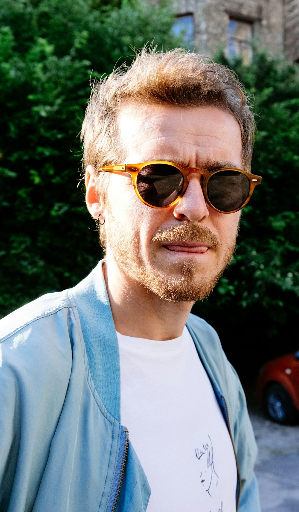 갈색 선글라스를 쓴 흰색 크루넥 셔츠를 입은 남자
