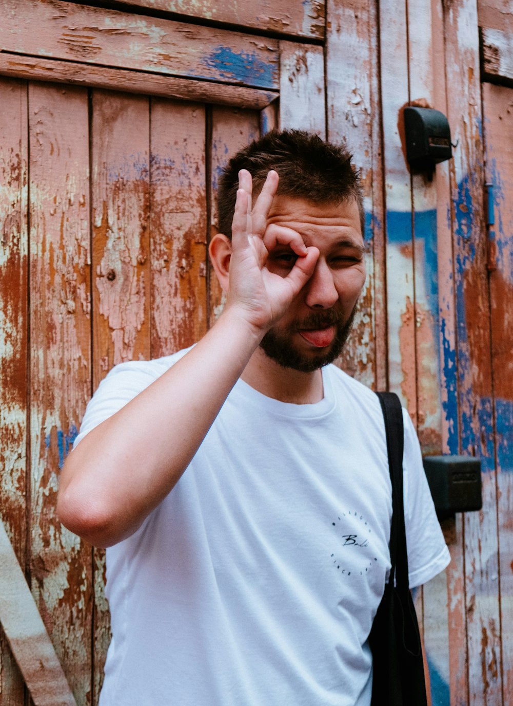 Hombre con camiseta blanca de cuello redondo que se cubre la cara con la mano