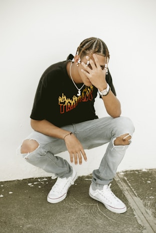 man in black crew neck t-shirt and blue denim jeans sitting on concrete floor