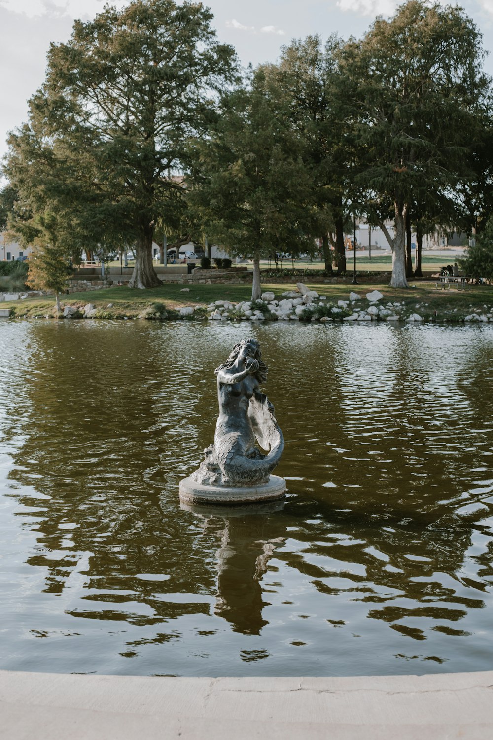 grey concrete fountain near green trees during daytime