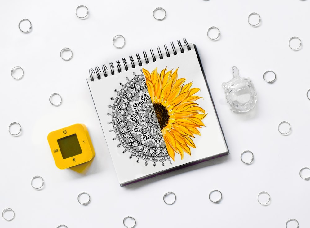 Weiße und gelbe Gänseblümchenblume auf weißem Spiralnotizbuch