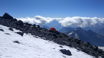 A sturdy tent pitched on a rocky mountain ledge at sunrise.