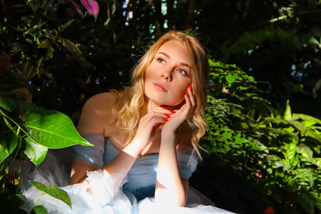 A serene morning scene with soft sunlight filtering through leaves onto a peaceful woman practicing gentle self-care.