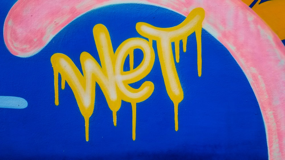 a blue wall with yellow and pink graffiti on it