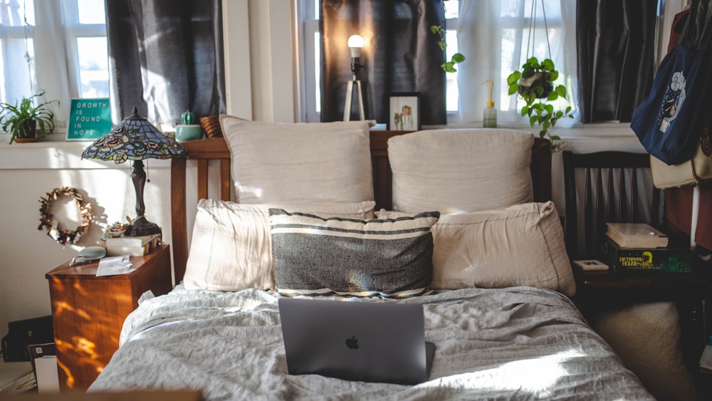 black laptop computer on white bed